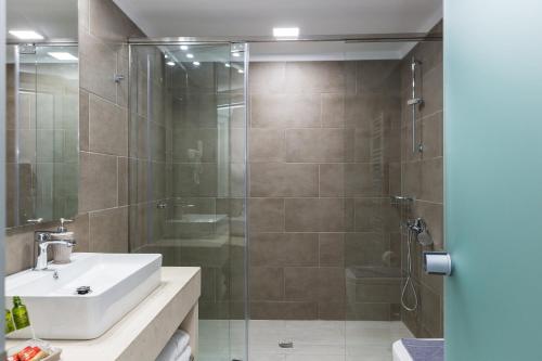 a bathroom with a glass shower with a sink and a toilet at Sun and Sea Plus Resort in Plaka