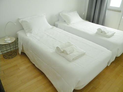 duas camas num quarto com lençóis brancos e toalhas em AL.Cova em Almada
