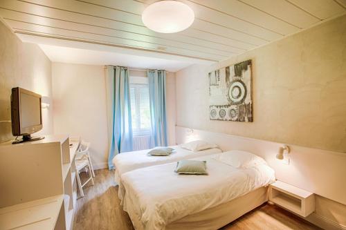 a hotel room with two beds and a television at L'Ile de Sees in Mac&eacute;