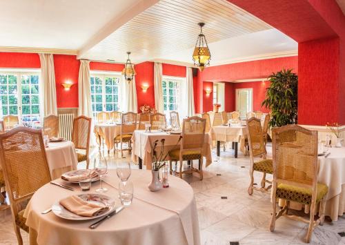 un restaurant avec des tables, des chaises et des murs rouges dans l'établissement L'Ile de Sees, à Macé