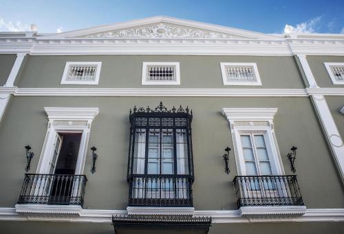 a white building with two windows and a gate at Hotel Boutique Conde de la Corte in Zafra
