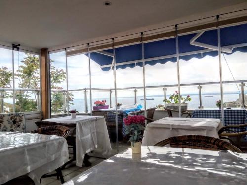 ボズジャ島にあるAdali Guest Houseのテーブルと椅子、大きな窓のあるレストラン