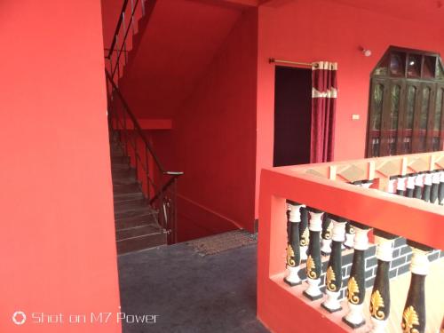 a red room with stairs and a red wall at Dekapara Airport Guest House in Kāhārpāra