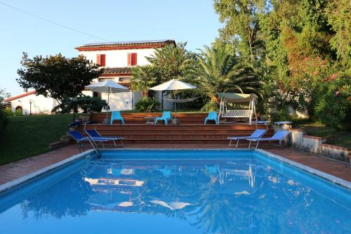 Villa Nerone B&B في Lorenzana: مسبح والكراسي الزرقاء والبيت