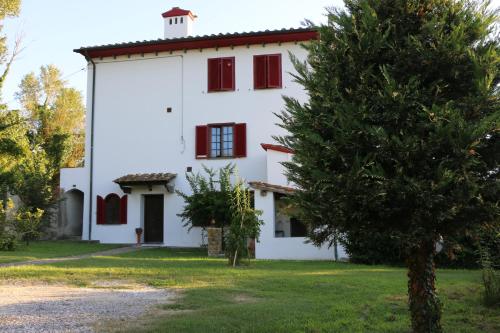 Villa Nerone B&B في Lorenzana: بيت ابيض بنوافذ حمراء وشجرة