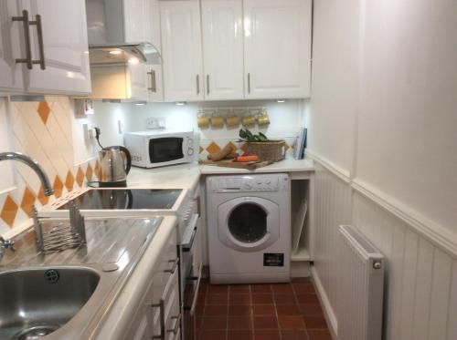 a kitchen with a washing machine and a microwave at Perfect for Caernarfon Castle, Snowdon, & Zip World in Caernarfon