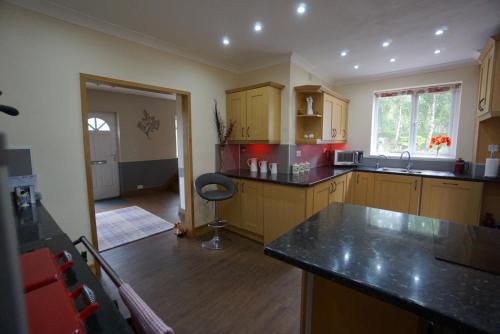 una cucina con armadi in legno e ripiani neri di West View Lodge a Basingstoke