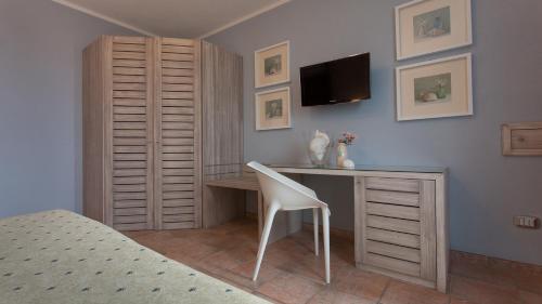 a bedroom with a desk and a bed and a tv at Boutique Hotel Ilio in SantʼAndrea