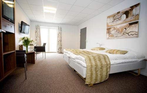 a bedroom with a bed and a desk and a television at Hotel Thinggaard in Hurup