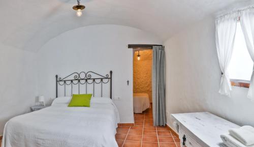 een slaapkamer met een wit bed en een groen kussen bij Casas Cueva Molino Fuencaliente in Huéscar