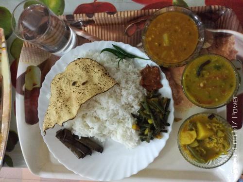 a plate of food with rice and other foods at Dekapara Airport Guest House in Kāhārpāra