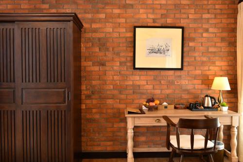 a brick wall with a table and a chair at El Barrio Lanna in Chiang Mai