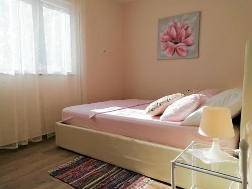 una camera da letto con letto e lenzuola e cuscini rosa di Apartment Vera Nin a Nin