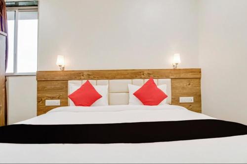 a bedroom with a white bed with red pillows at Hotel Star Zest House in Nagpur