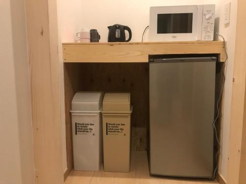 a kitchen with a microwave and two trash cans under a counter at Sapporo Guest House 庵 Anne in Sapporo