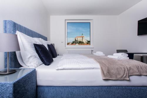 a bedroom with a large white bed with a window at Penzion Čáp in Mikulov