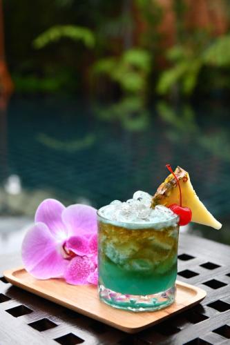 a drink on a plate with a flower and a cocktail at El Barrio Lanna in Chiang Mai