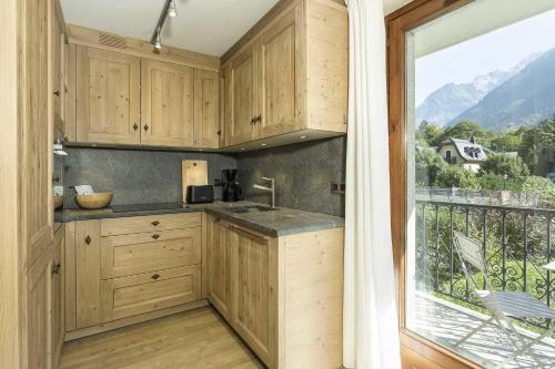 une cuisine avec des placards en bois et une grande fenêtre dans l'établissement APARTMENT ENSA - Alpes Travel - Central Chamonix - Sleeps 4, à Chamonix-Mont-Blanc