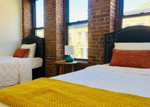 a bedroom with two beds and a brick wall at Two Bedroom Harlem Apartment in New York