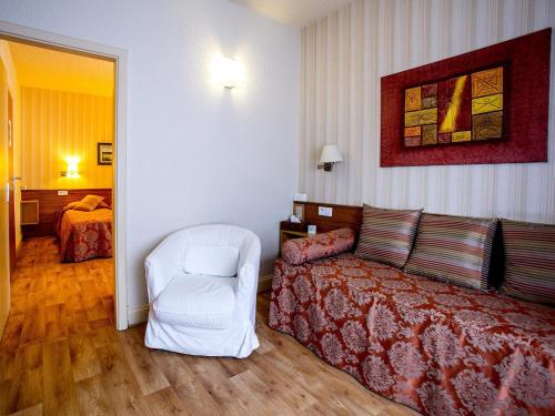 a hotel room with a bed and a white chair at Logis Hôtel Restaurant La Tête Des Faux in Le Bonhomme