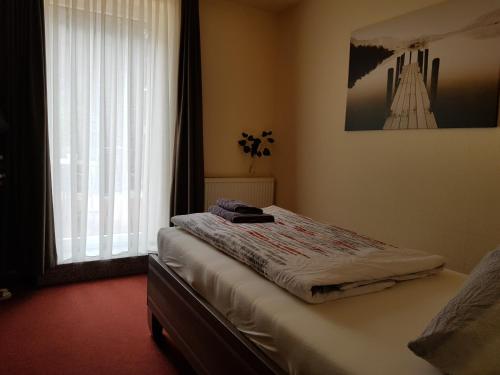 a bed in a room with a window and avertisement at Hotel Zwei Linden in Ottendorf-Okrilla