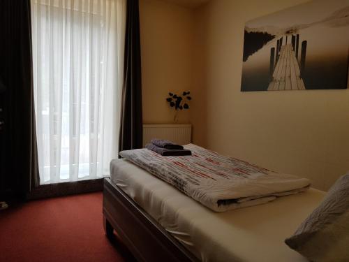 Bett in einem Zimmer mit Fenster und Avertisation in der Unterkunft Hotel Zwei Linden in Ottendorf-Okrilla