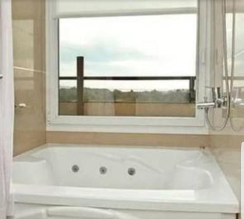 baño con bañera blanca y ventana a Linda Bay Dúplex 221 en Mar de las Pampas