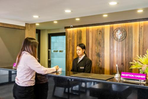 a woman standing in front of a desk with a man at Livotel Express Hotel Ramkhamhaeng 50 Bangkok - No Parking in Bangkok