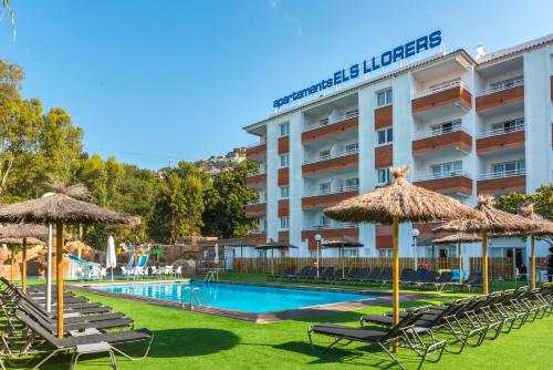 un hotel con piscina, sillas y sombrillas en Apartaments Els Llorers, en Lloret de Mar