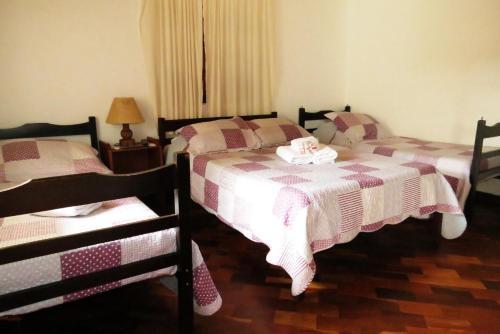 a bedroom with two beds and a table with a lamp at Pousada Toca das Bromelias in Campos do Jordão