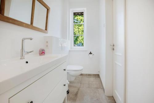 La salle de bains blanche est pourvue de toilettes et d'une fenêtre. dans l'établissement Ferien Hohes Elbufer, à Schnakenbek