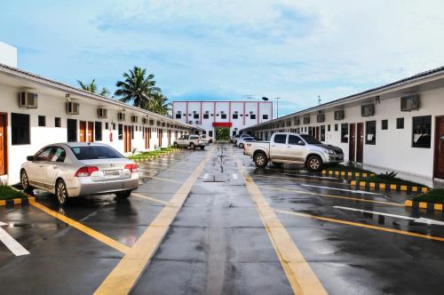 un aparcamiento con coches estacionados frente a los edificios en Aquarius Hotel Aquarius en Ariquemes