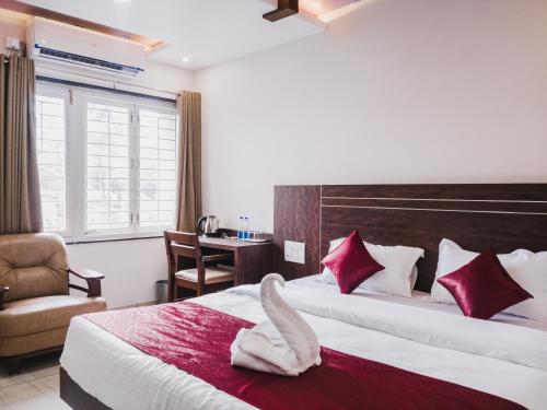Habitación de hotel con 2 camas y toallas rojas y blancas en D' Manor Service Apartment, en Belgaum