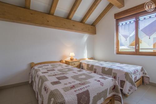 een slaapkamer met 2 bedden en een raam bij Gîtes de la Bresse in Saint-Georges-des-Hurtières