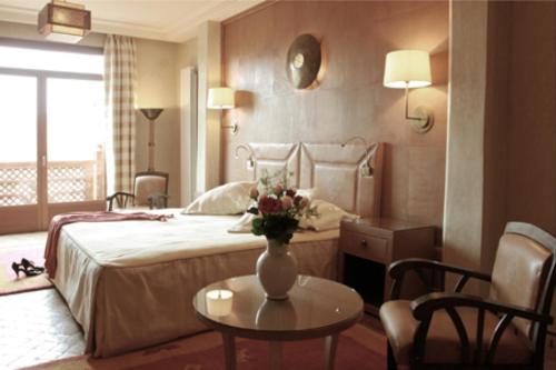 a bedroom with a bed and a table with a vase of flowers at La Maison Arabe Hotel, Spa & Cooking Workshops in Marrakech