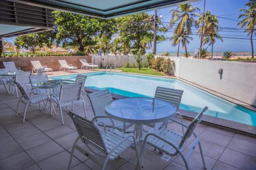 a patio with tables and chairs next to a swimming pool at Luxor Cabo Branco Home Service in João Pessoa