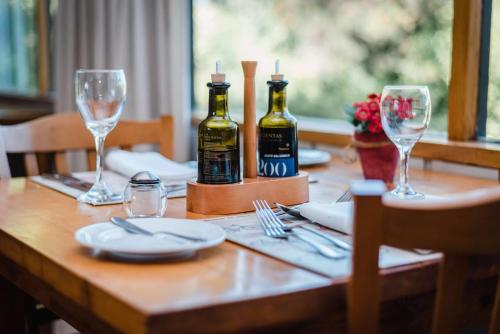 a wooden table with two bottles of wine and glasses at Hotel El Ciervo in Villarrica