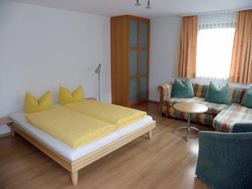 a bedroom with a yellow bed and a couch at Chasa Vaidum in Samnaun