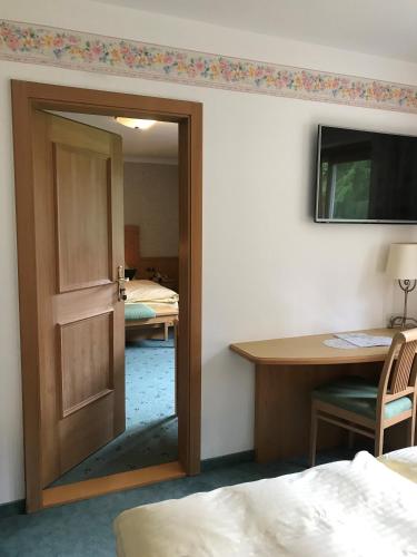 a door leading into a room with a desk and a bedroom at Heutaler Hof - Hotel im Naturidyll in Unken