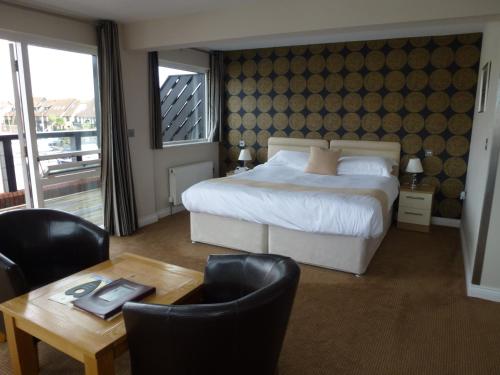 a bedroom with a bed and a table with chairs at Boathouse Hotel in Hythe