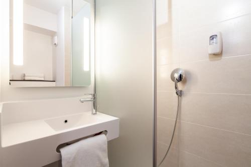 La salle de bains blanche est pourvue d'un lavabo et d'une douche. dans l'établissement B&B HOTEL Compiègne, à Compiègne