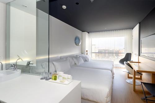 Habitación de hotel con cama, escritorio y lavabo. en Barceló Sants, en Barcelona