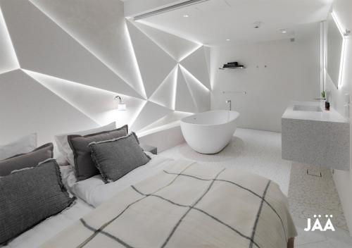 HAAWE Boutique Apart Hotel في روفانييمي: غرفة نوم مع سرير وحوض استحمام ومغسلة