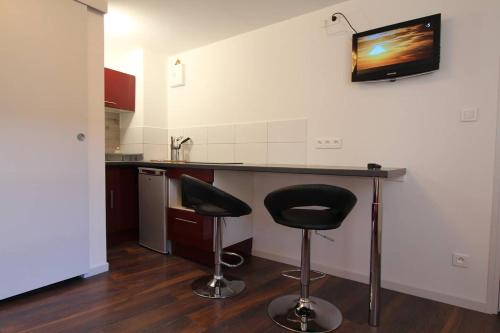 a kitchen with a counter and two stools in it at Chambre chez l'habitant Le Rouge-Gorge - Cœur de Riquewihr - 2 personnes in Riquewihr