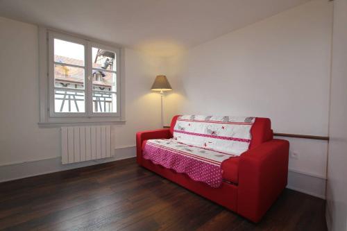 ein rotes Sofa in einem Zimmer mit Fenster in der Unterkunft Chambre chez l'habitant Le Rouge-Gorge - Cœur de Riquewihr - 2 personnes in Riquewihr