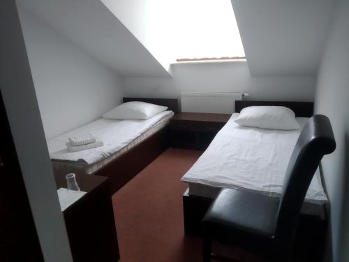 2 Betten in einem Zimmer mit einem Stuhl und einem Fenster in der Unterkunft Zajazd Rosa in Stoczek Łukowski