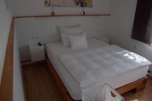 a bedroom with a large white bed with two night stands at Apartmenthaus Erlenbach in Erlenbach