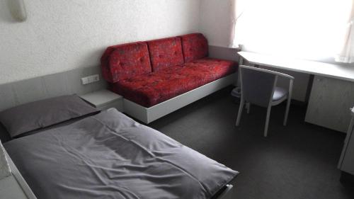 Cette chambre comprend un lit et un canapé rouge. dans l'établissement Hotel Carle, à Deizisau