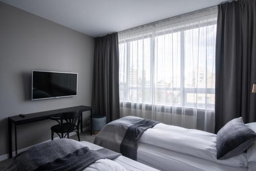 a hotel room with two beds and a desk and a window at Reykjavik Residence Apartment Hotel in Reykjavík
