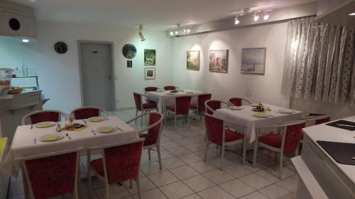 un restaurant avec des tables blanches et des chaises rouges dans l'établissement Hotel Carle, à Deizisau